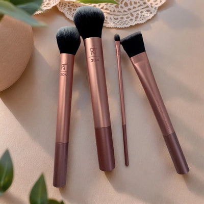 Set of Real Techniques makeup brushes displaying nylon bristles and plastic handles on a soft background.