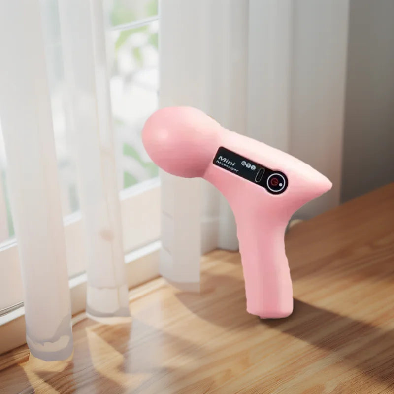 Portable electric muscle massage gun in pink color on a wooden table, ideal for deep tissue massage.